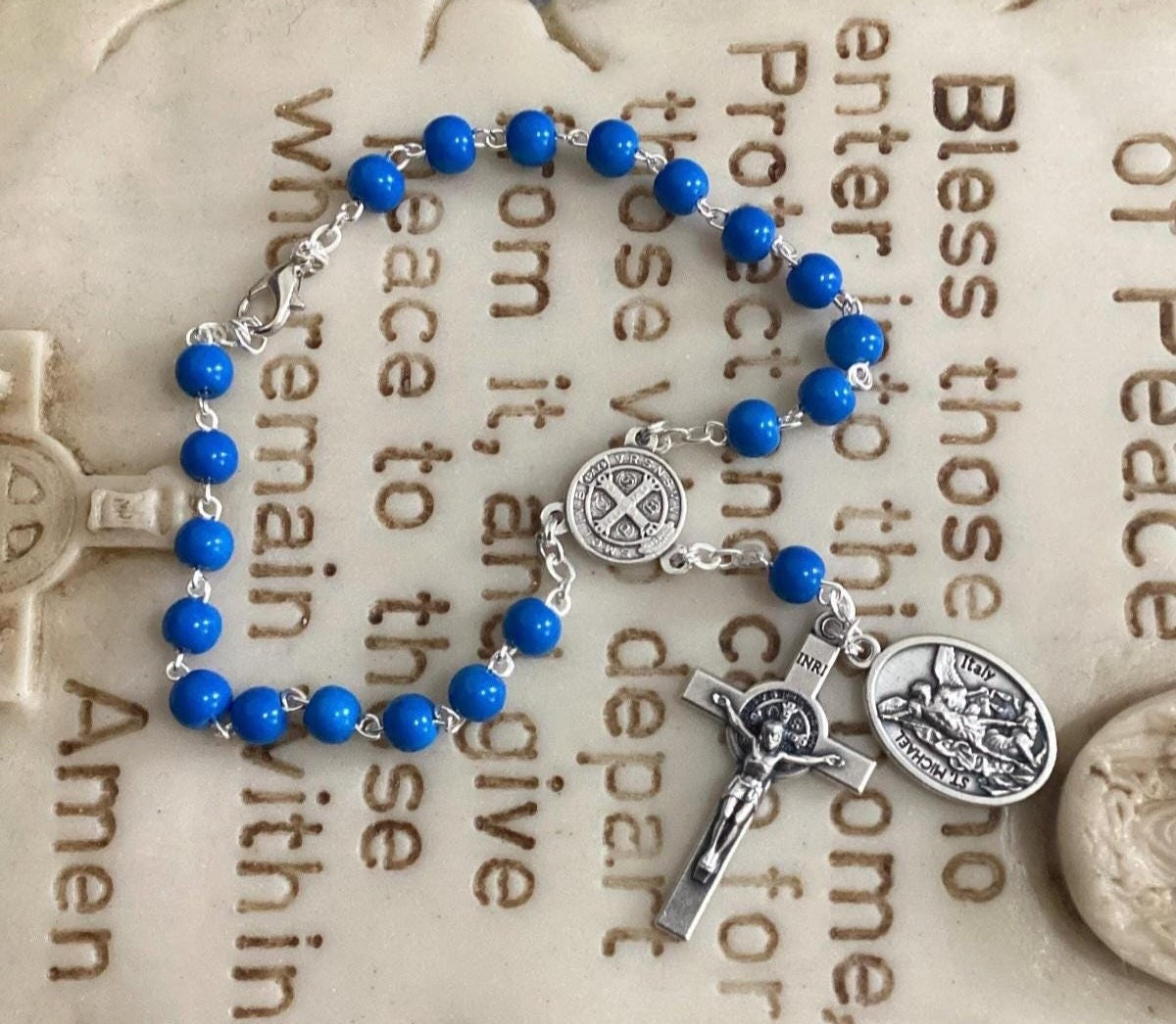 Car rosary hanging from rearview mirror with crucifix and medal