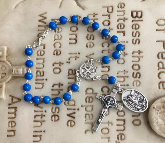 Car rosary hanging from rearview mirror with crucifix and medal