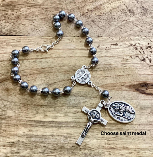 Car rosary hanging from rearview mirror with crucifix and medal